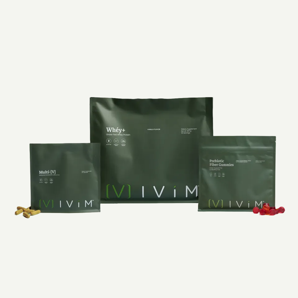 Three dark green IViM supplement pouches arranged on a light gray background, with small amounts of capsules or powder placed in front of each package. Visible text includes IViM, Whey+, Multi-Nutrients, and Probiotic Fiber Gummies.