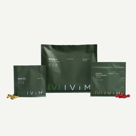 Three dark green IViM supplement pouches arranged on a light gray background, with small amounts of capsules or powder placed in front of each package. Visible text includes IViM, Whey+, Multi-Nutrients, and Probiotic Fiber Gummies.